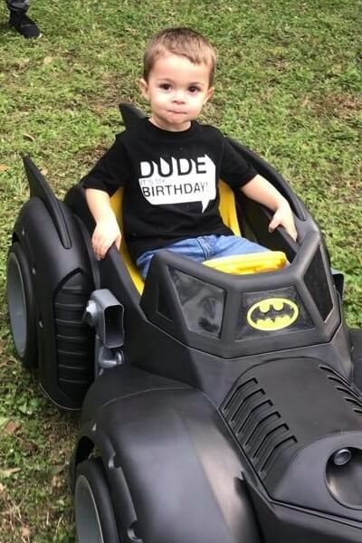 jess fuentes tubal reversal baby at his 2-year birthday party sitting in a toy batmobile car