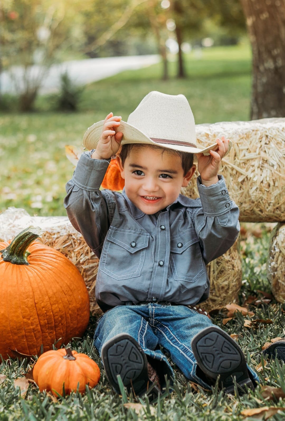 NORA knight's tr baby boy in a cowboy hat sitting with pumpkins and bales of hay
