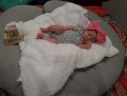 kimberly mills' first tubal reversal baby is a girl laying on a blanket with a giant pink bow on her head