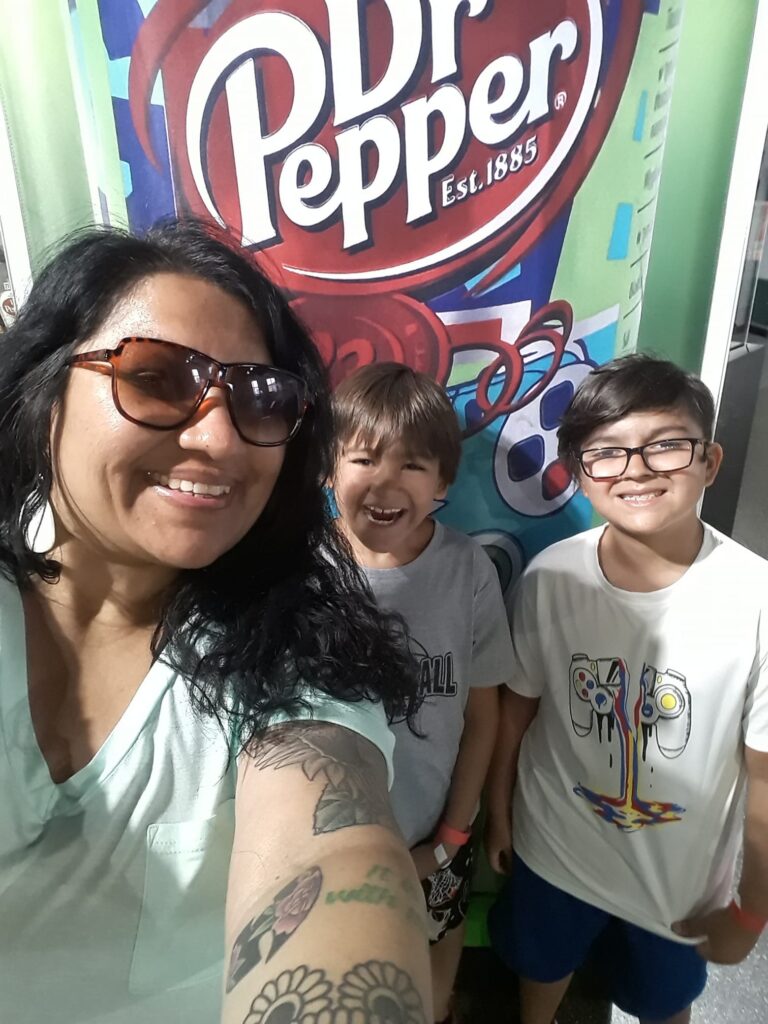 maria lopez with her older tubal reversal boys in front of a dr pepper vending machine