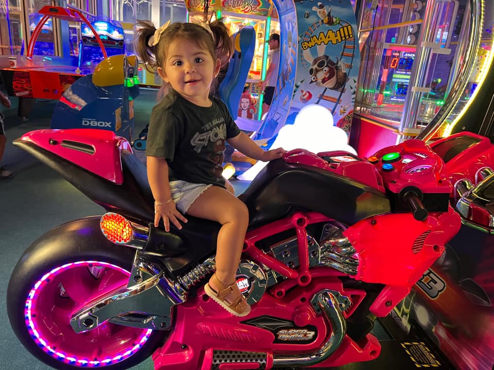 baylee hurtado, a tubal reversal baby now 2 years old on a motorcycle game in the arcade