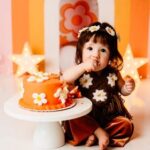 connie hyles tubal reversal baby turned 1 wearing a flower child outfit eathing a flower power cake