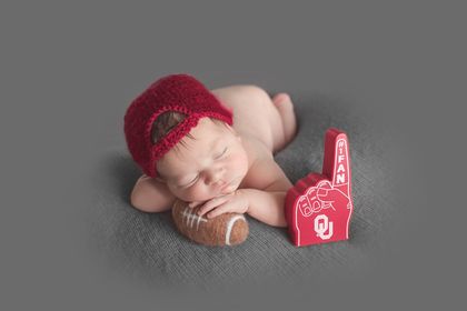 newborn picture of amanda fay albright' second tubal reversal baby boy wearing a baseball cap holding a football