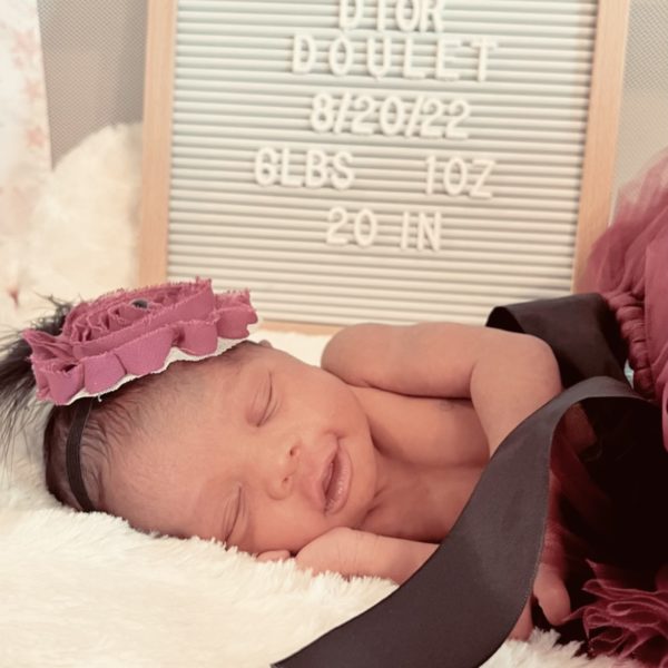newborn tr baby girl named phenix sleeping with a birth announcement board behind her
