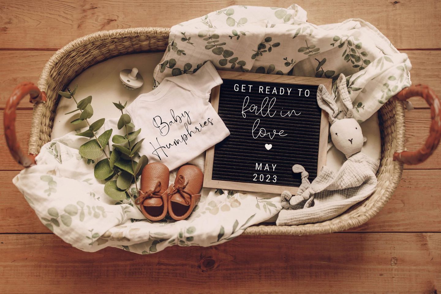 shelby lynn campbell humphries tr baby announcement features baby shoes, baby blanket, stuffed rabbit, and chalkboard making the announcement all in a straw basket