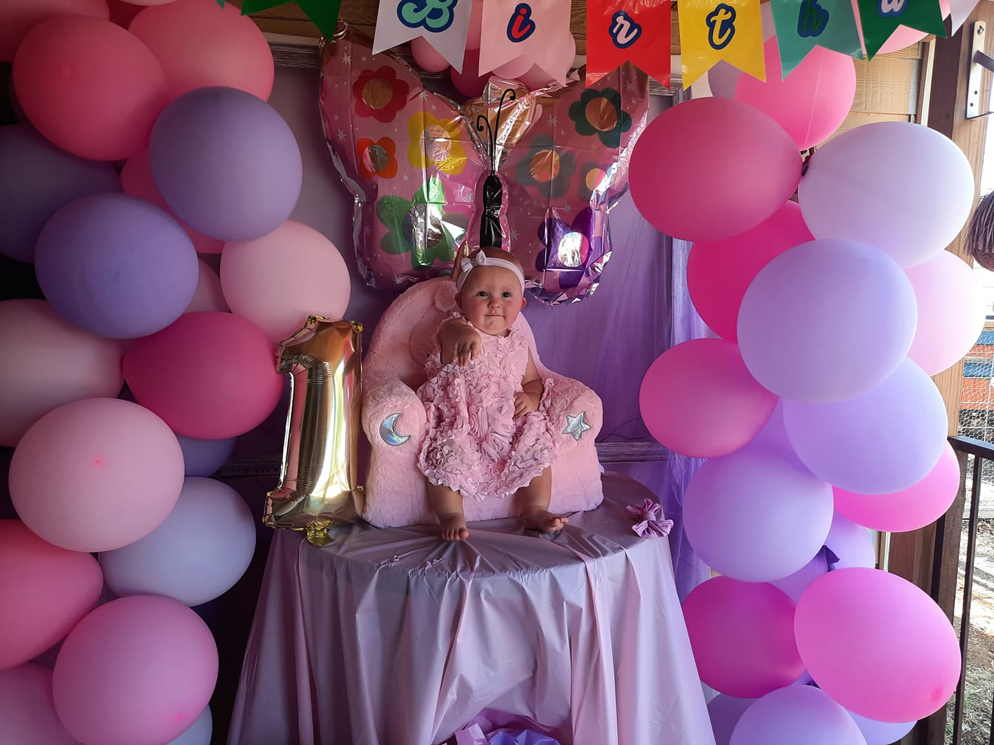perla hodgkins' tubal reversal baby surrounded by pink balloons at her 1st birthday party